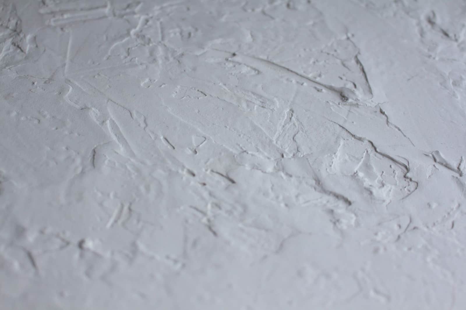 Close-up shot of a textured white plaster surface with rough details.